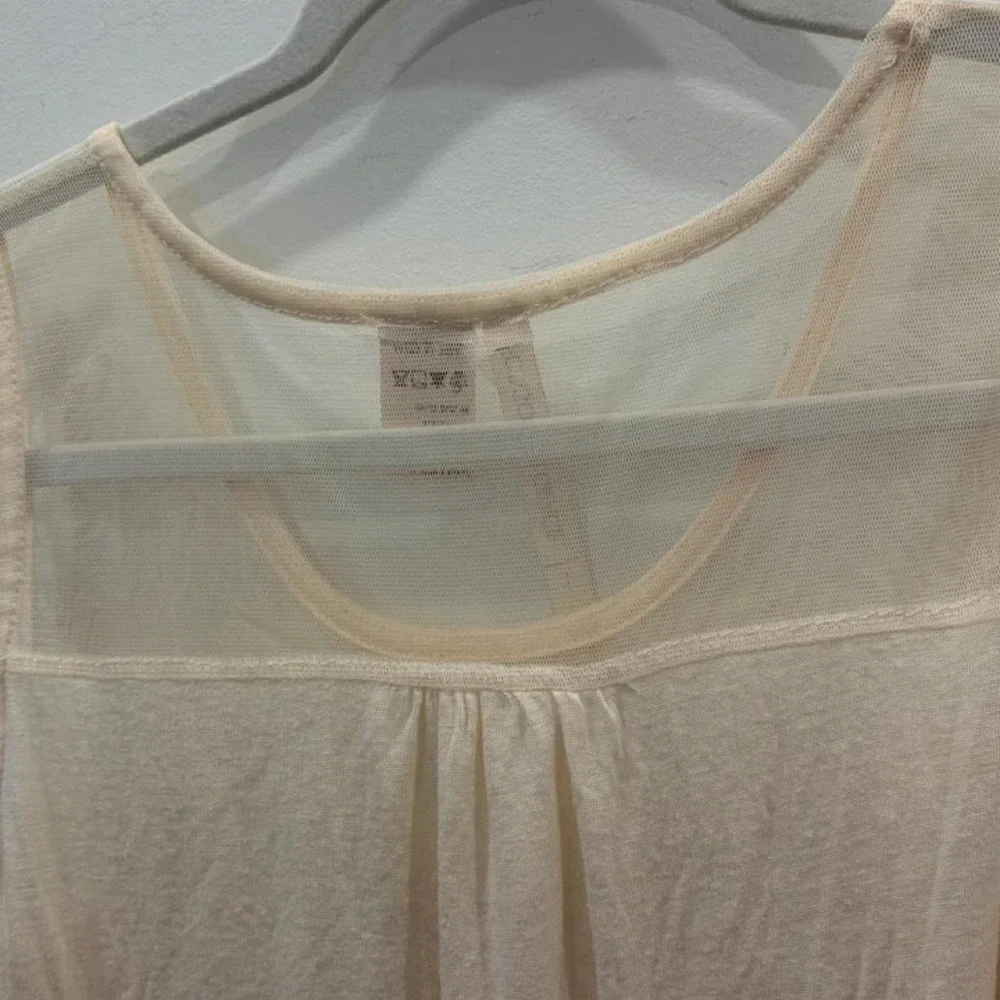 Cream lace tank top with sheer mesh and lace trim on the shoulders
